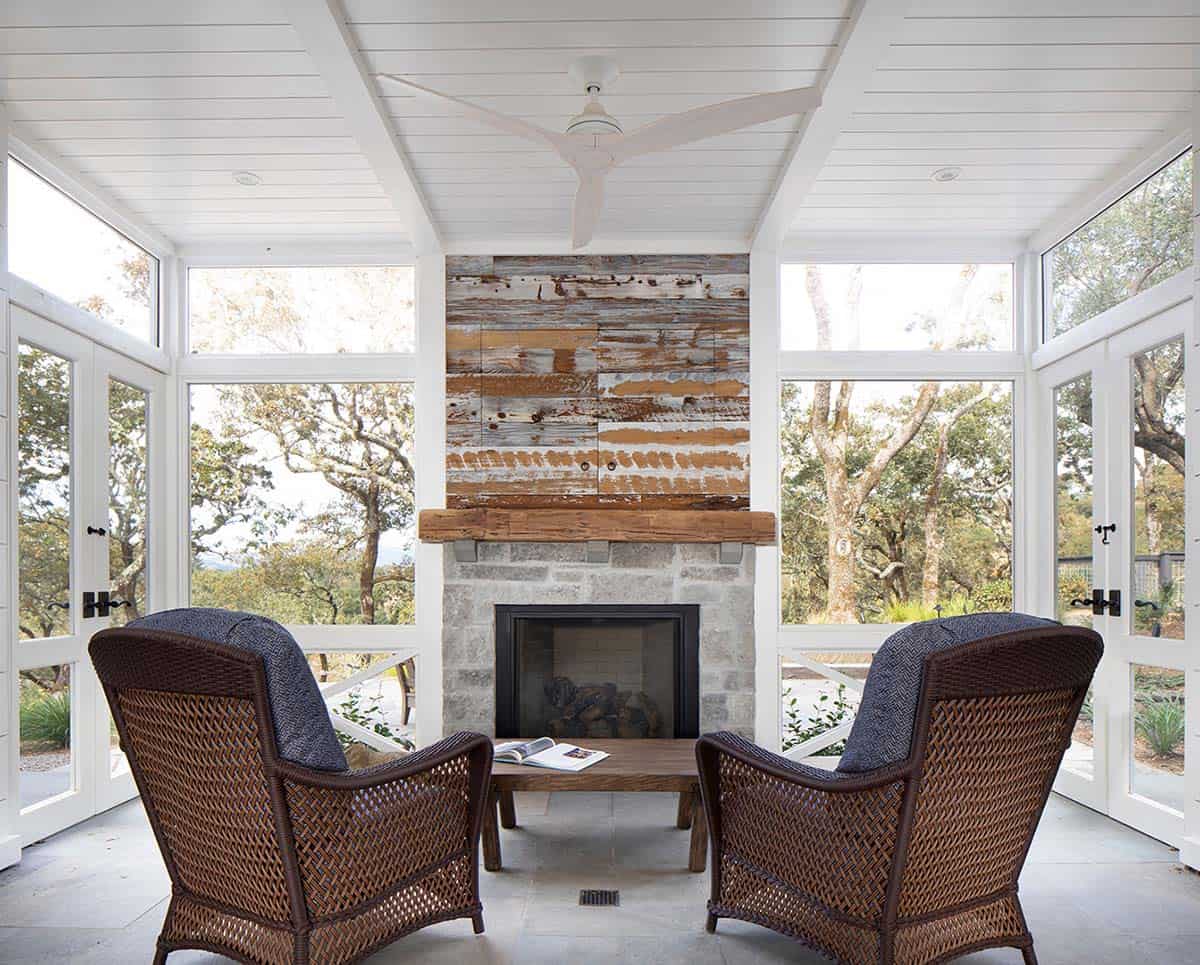 Screened porch sitting area with stone fireplace and wicker armchairs