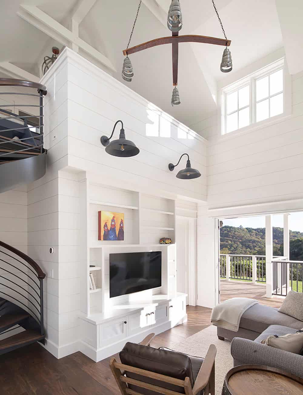 Living room with spiral staircase, built-in white shelving, and industrial pendant chandelier