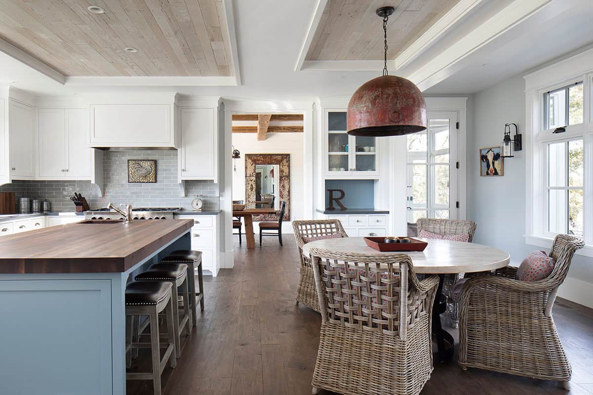 Kitchen with wicker dining chairs, blue island, and view into adjacent dining room