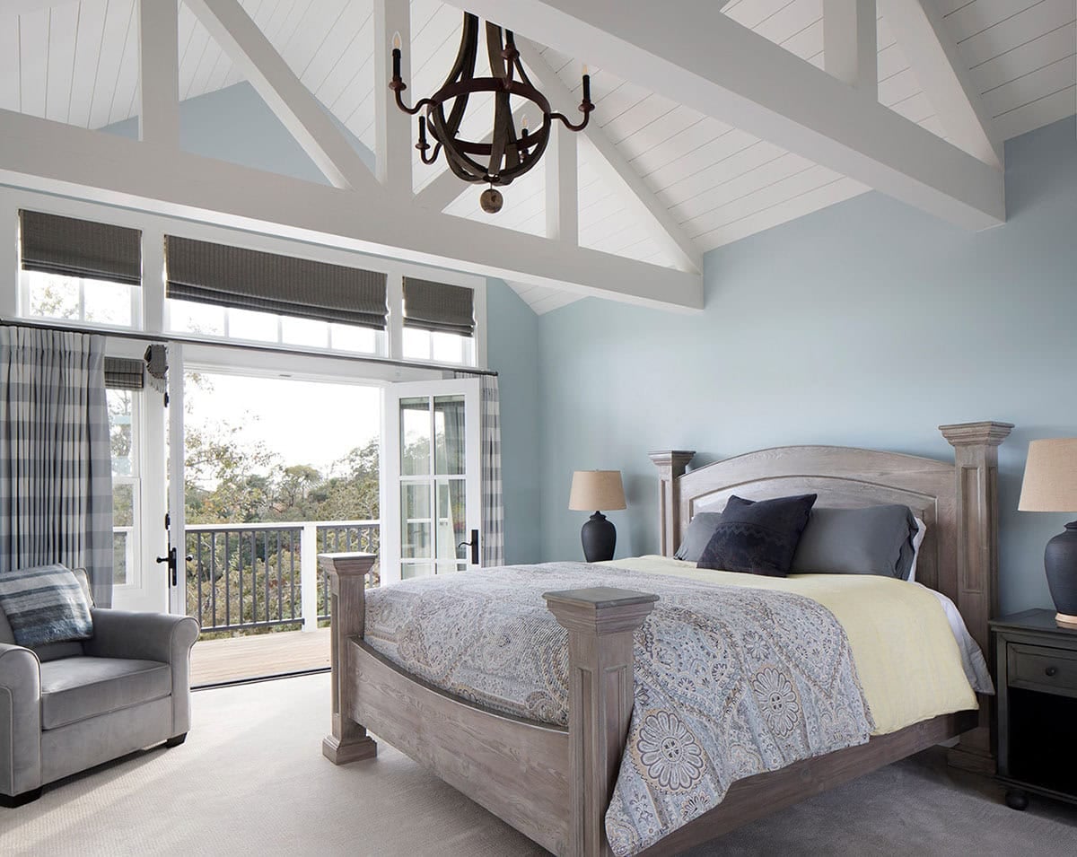 Primary bedroom with vaulted shiplap ceiling, wood bed, and French doors to a balcony