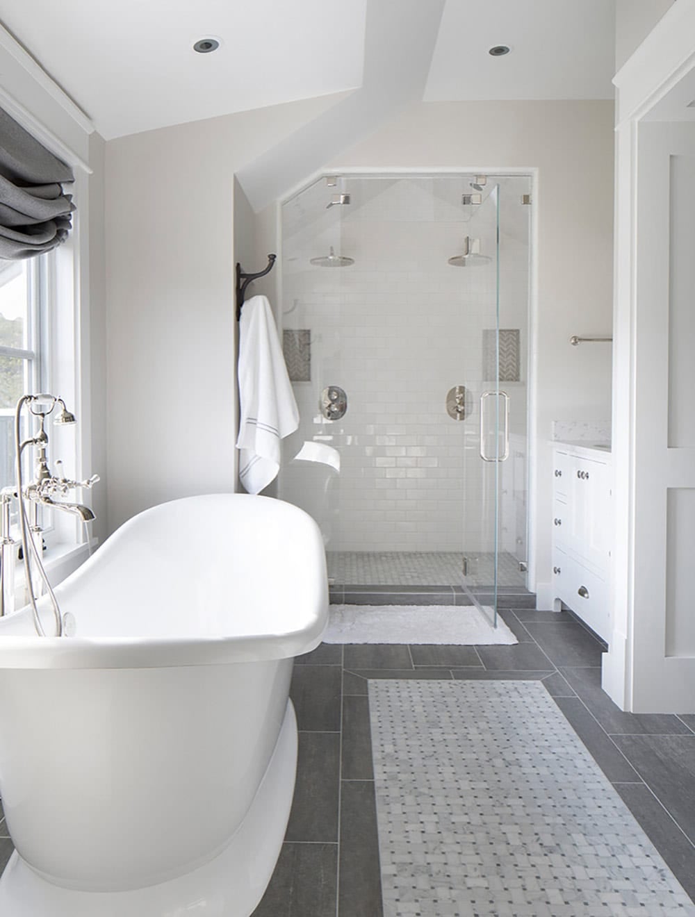 Bathroom with freestanding tub, glass-enclosed shower, and gray tile flooring