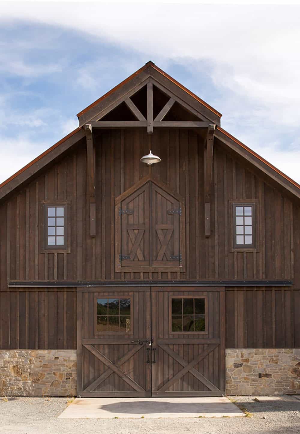Close-up of a wooden barn's gable end with X-braced doors and small windows