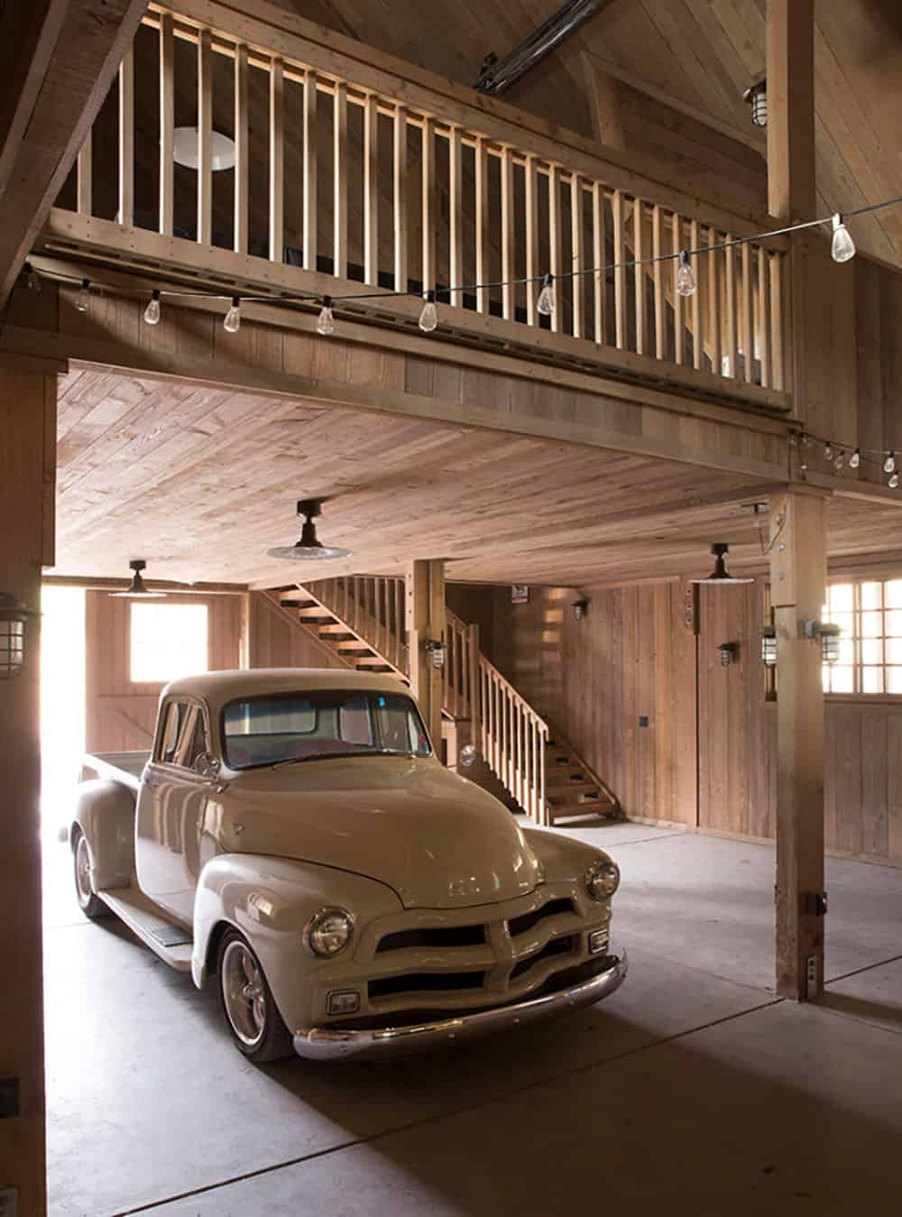 Barn interior with a vintage pickup truck parked beneath a wood-railed loft