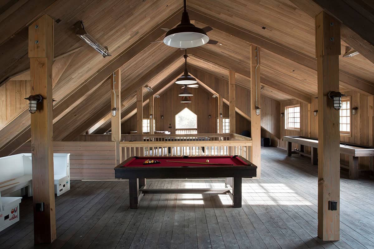 Barn loft game room with pool table, shuffleboard, and vaulted wood-paneled ceiling