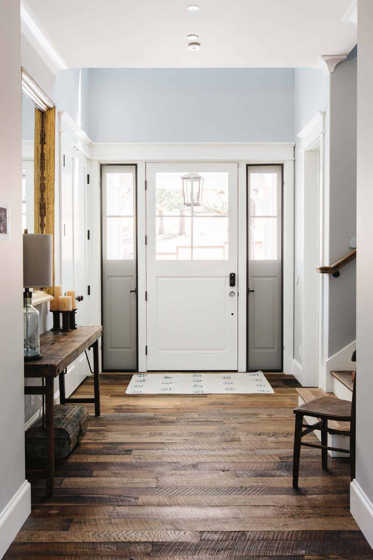 Entryway with reclaimed wood floors, glass-paned front door, and rustic console table