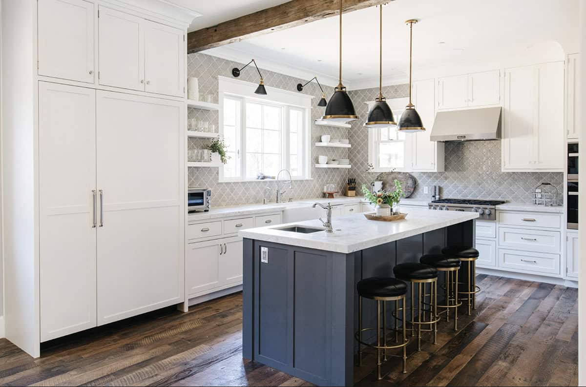 White kitchen with navy island, black pendant lights, and diamond-patterned tile backsplash