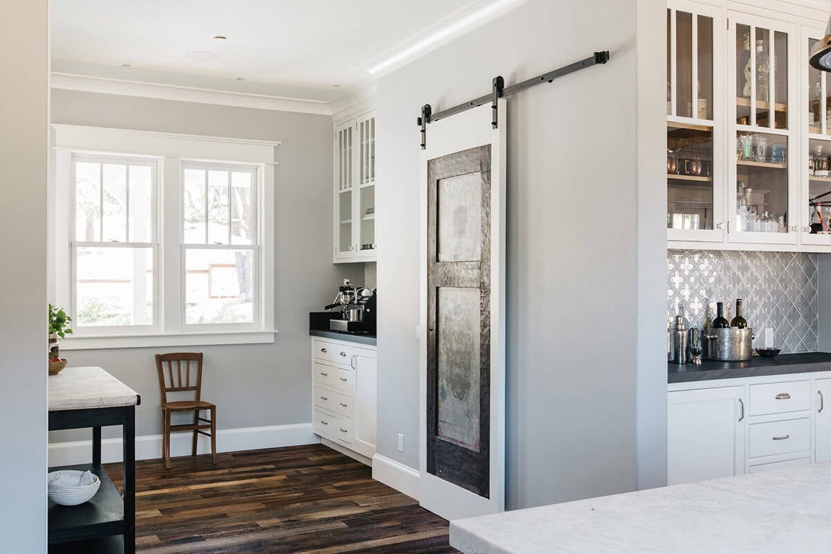 Butler's pantry with sliding barn door, espresso machine, and glass bar cabinets