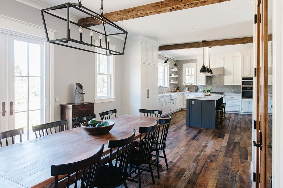 Dining area with wood table, black windsor chairs, and view into the kitchen