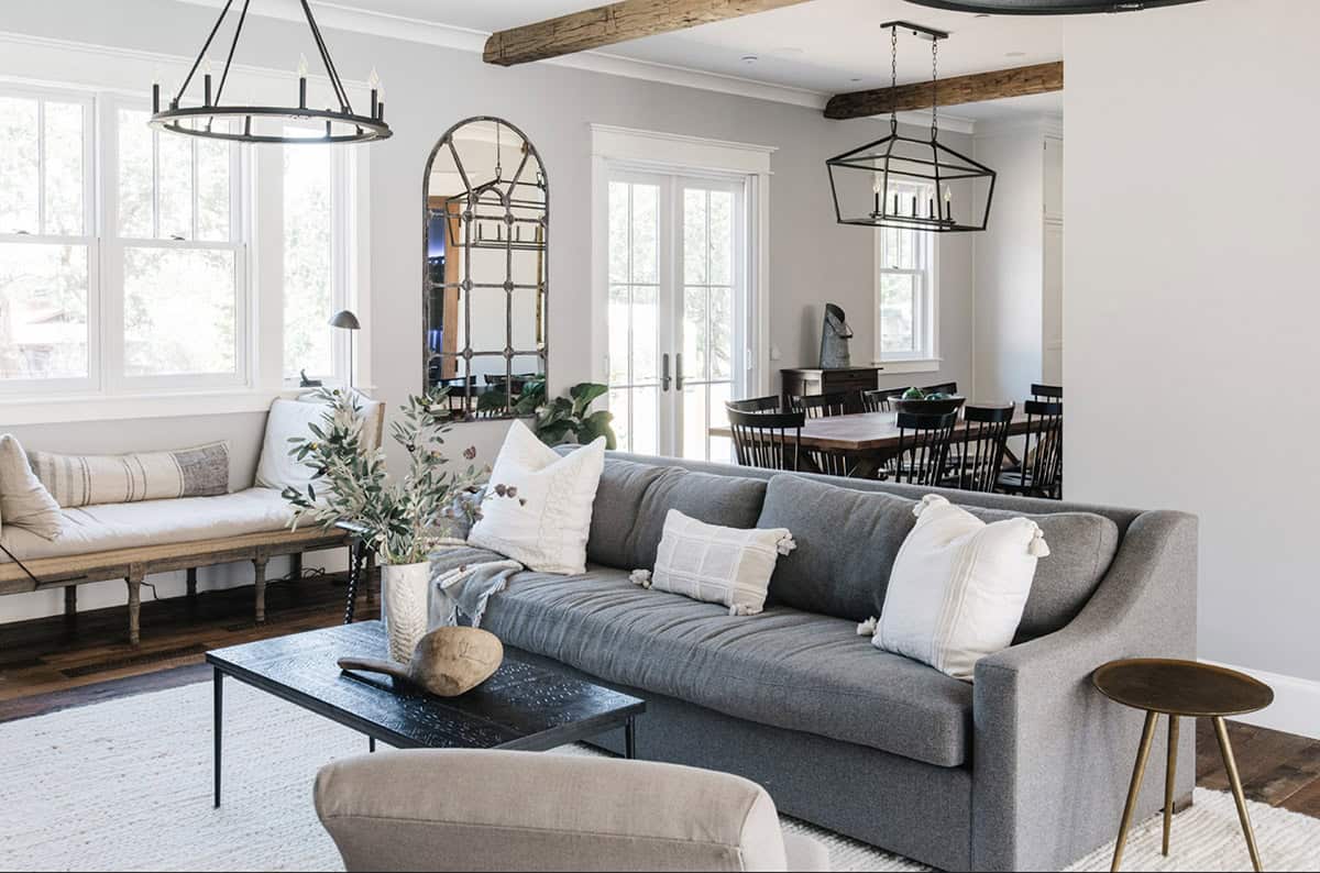 Living room with gray sectional, wood beams, and arched mirror