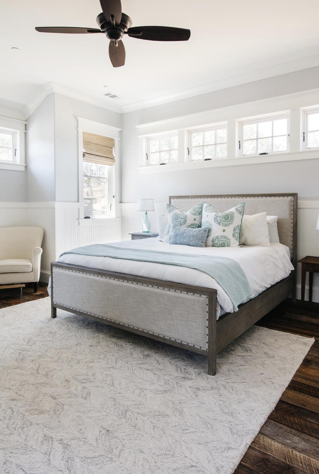 Bedroom with upholstered bed, ceiling fan, and rows of transom windows