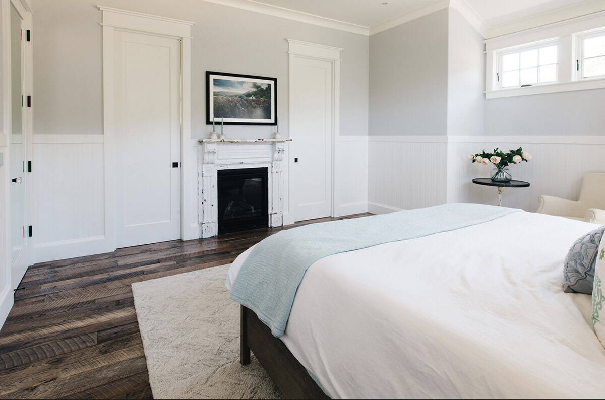 Bedroom corner with vintage white fireplace mantel and reclaimed wood floors