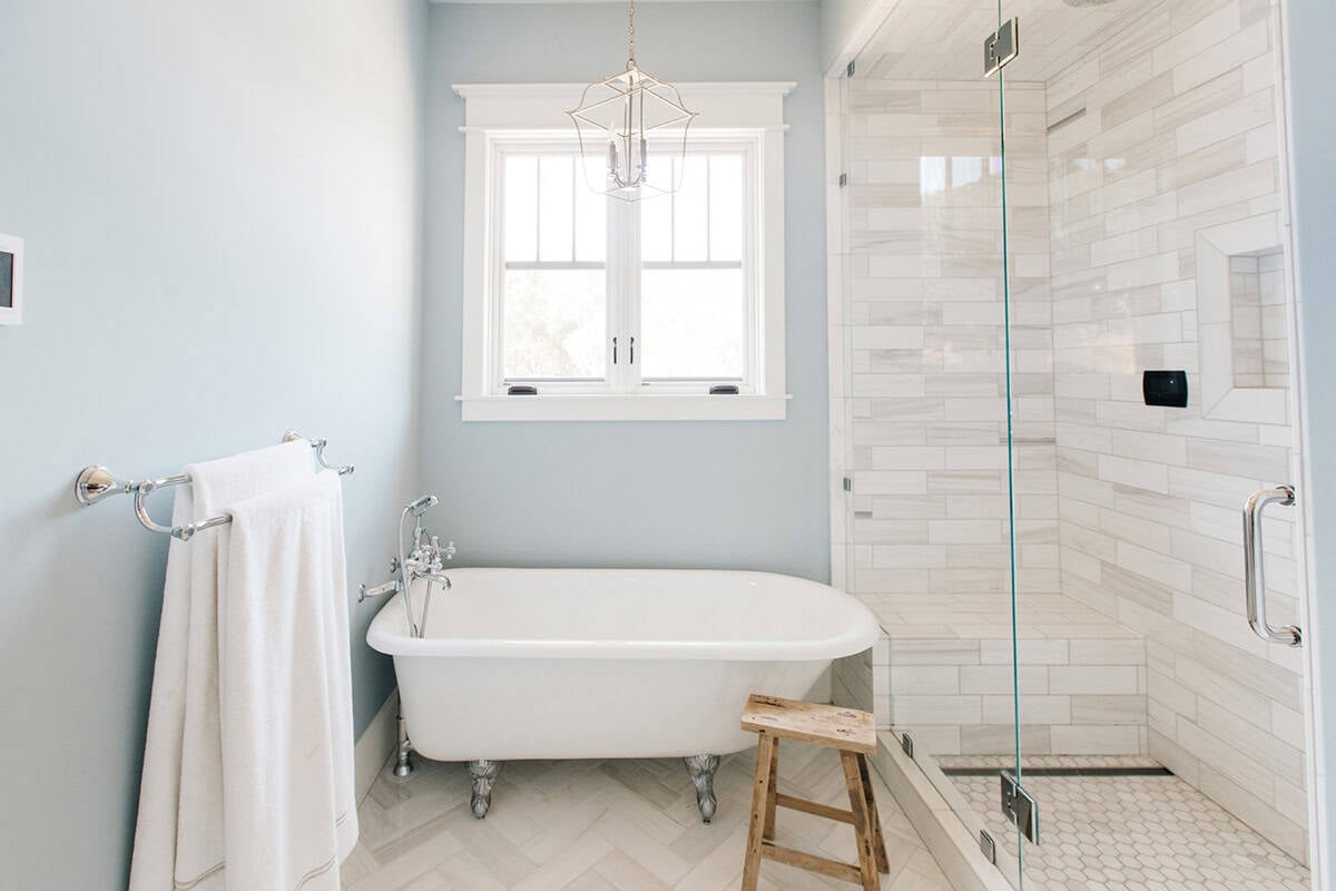 Bathroom with clawfoot soaking tub, glass shower, and marble subway tile