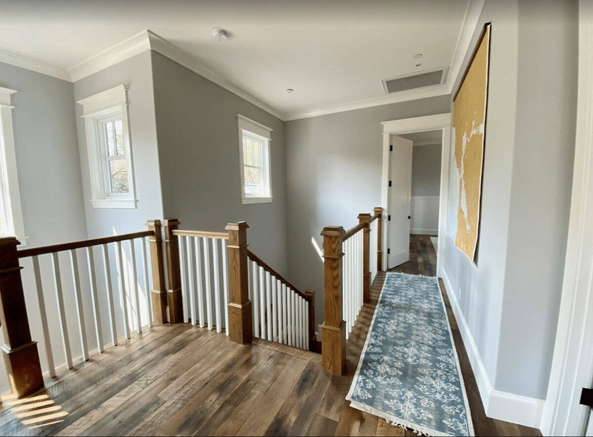 Upstairs hallway with reclaimed wood floors, staircase, and blue runner rug