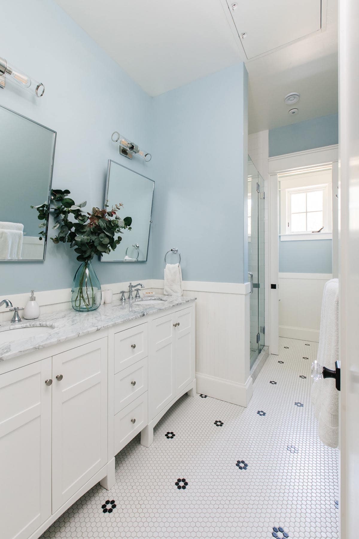 Blue bathroom with double vanity, marble countertop, and honeycomb tile floor