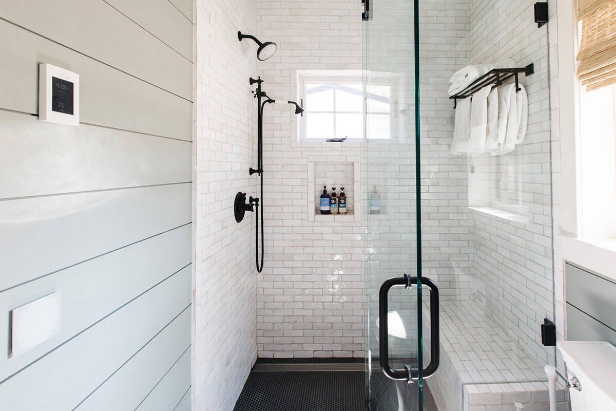 Walk-in shower with white subway tile, black fixtures, and built-in niche