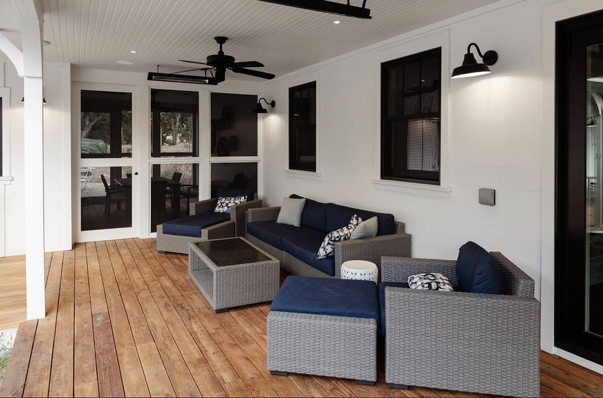 Screened porch with navy wicker furniture and black gooseneck sconces