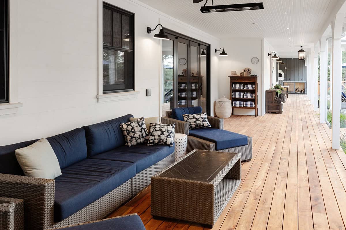 Covered porch walkway with navy seating, towel storage, and view toward outdoor kitchen