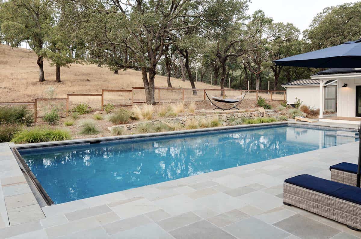 Pool overlooking oak-studded hillside with hammock and stone patio