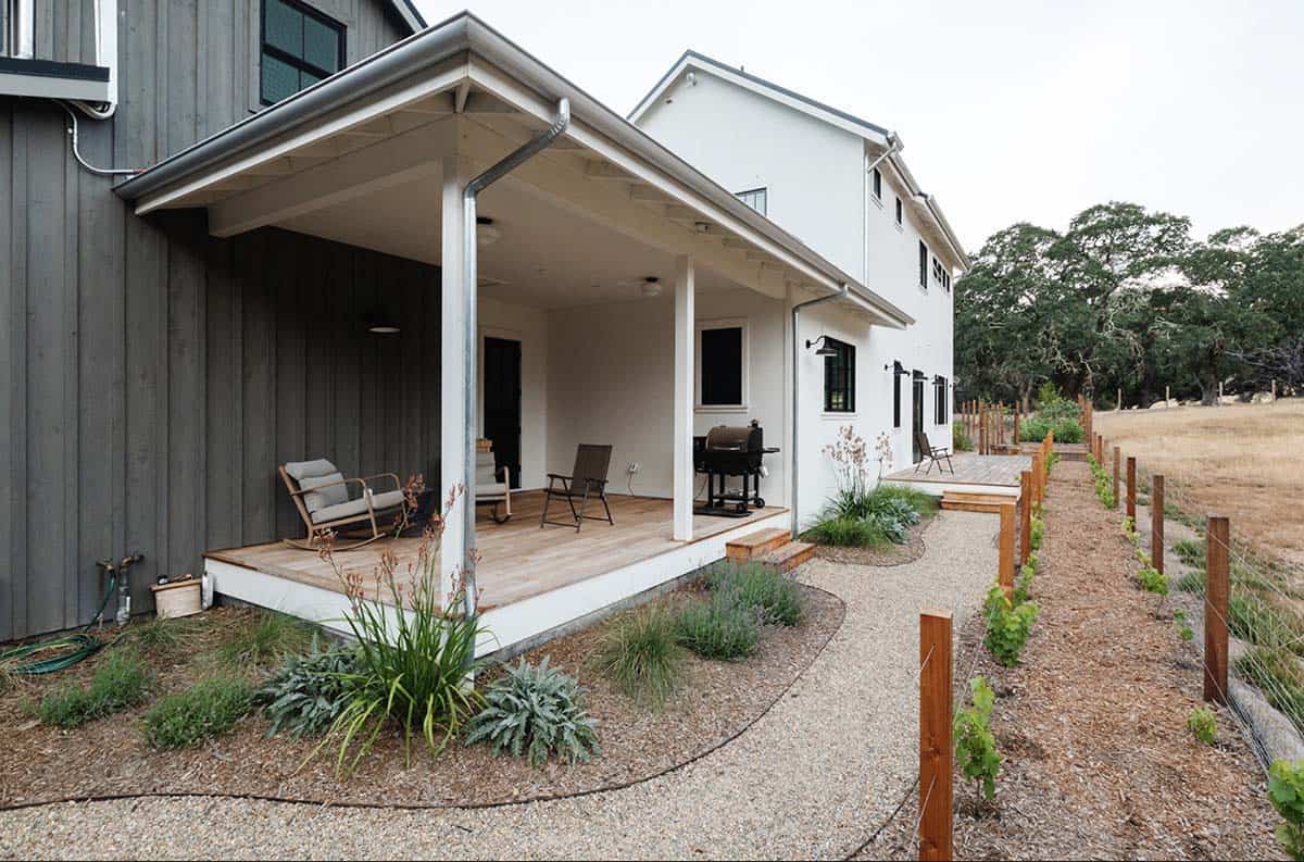 Side exterior with covered porch, rocking chairs, grill, and vineyard rows