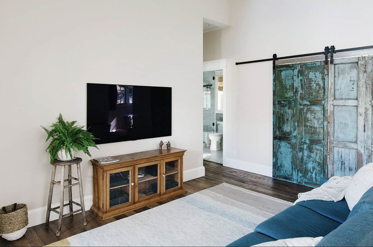 Living room with sliding patina barn doors, wood TV console, and blue sofa