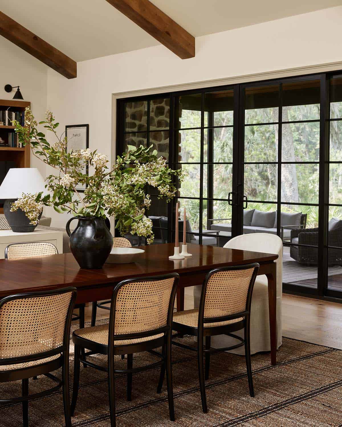 Dining table with black cane chairs facing steel garden doors