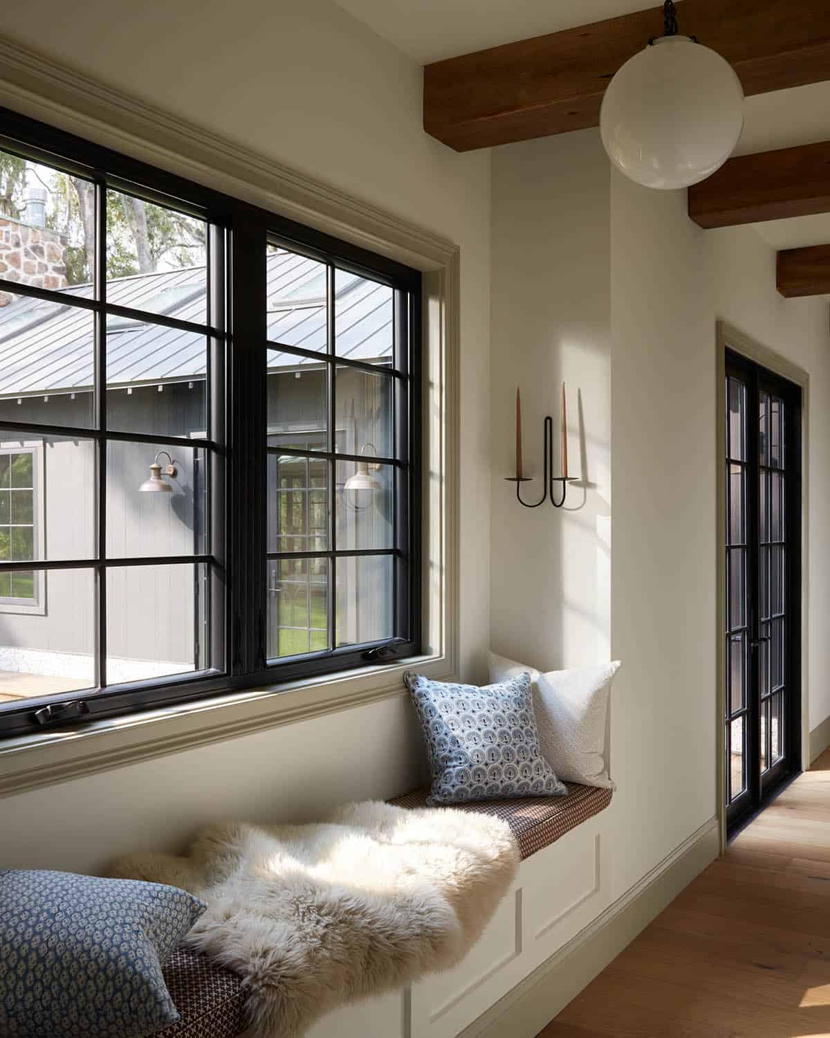 Window seat nook with sheepskin throw and black steel windows