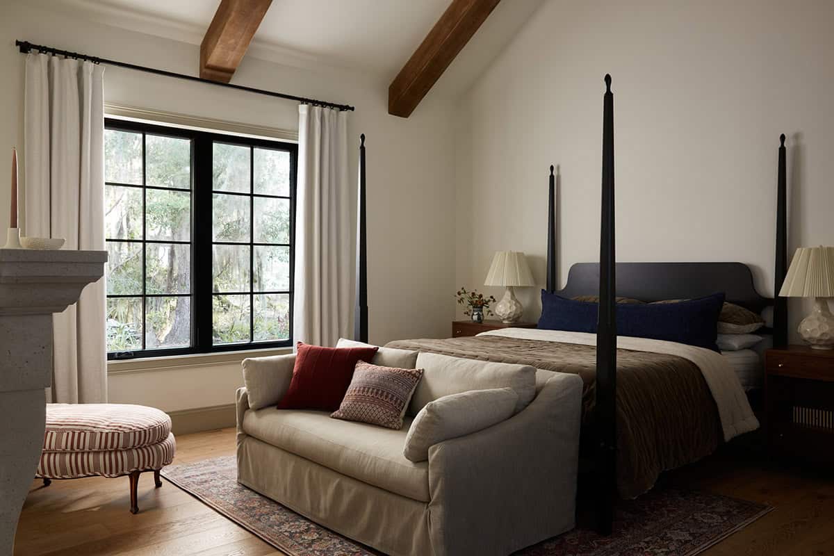 Primary bedroom with black four poster bed and vaulted beams