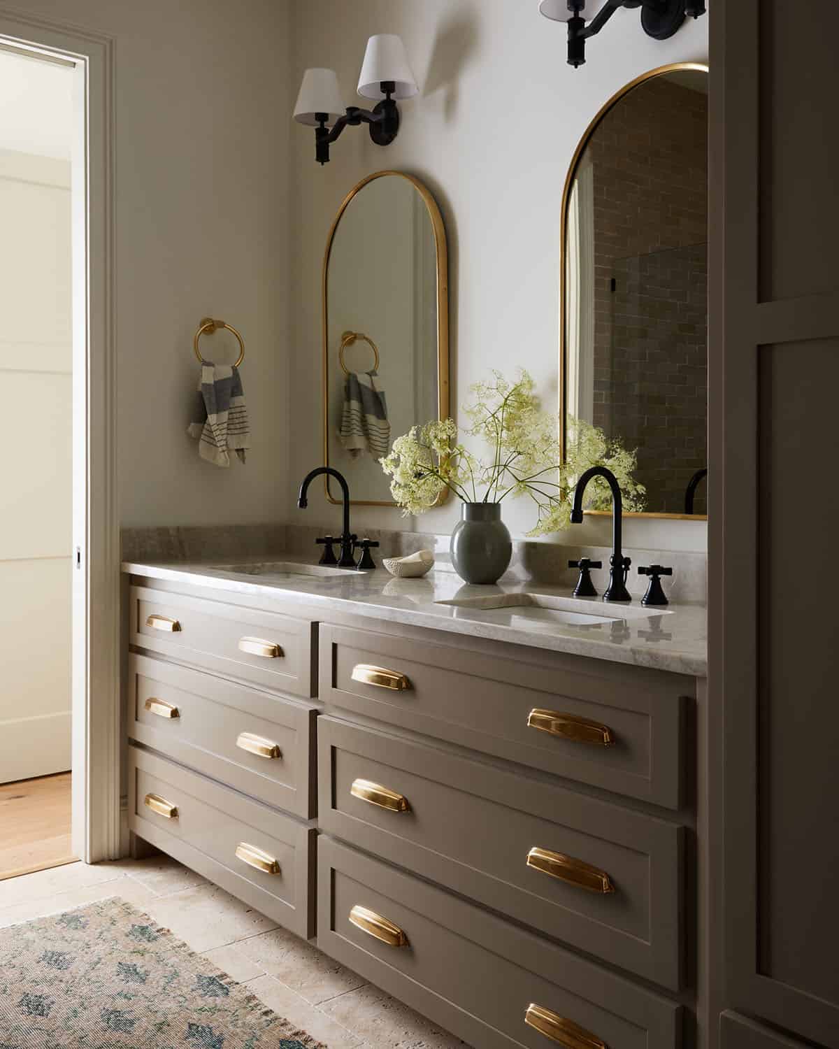 Double vanity with brass cup pulls and arched brass mirrors