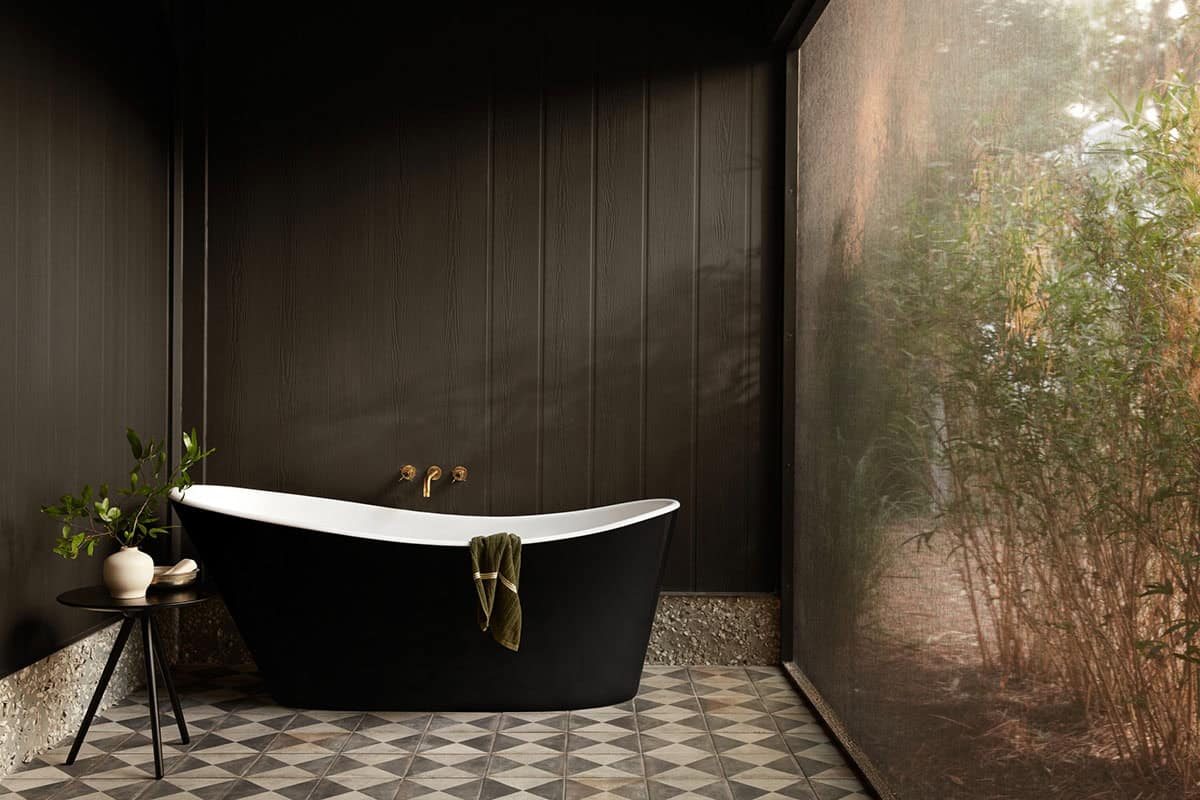 Black soaking tub in dark paneled outdoor bath enclosure
