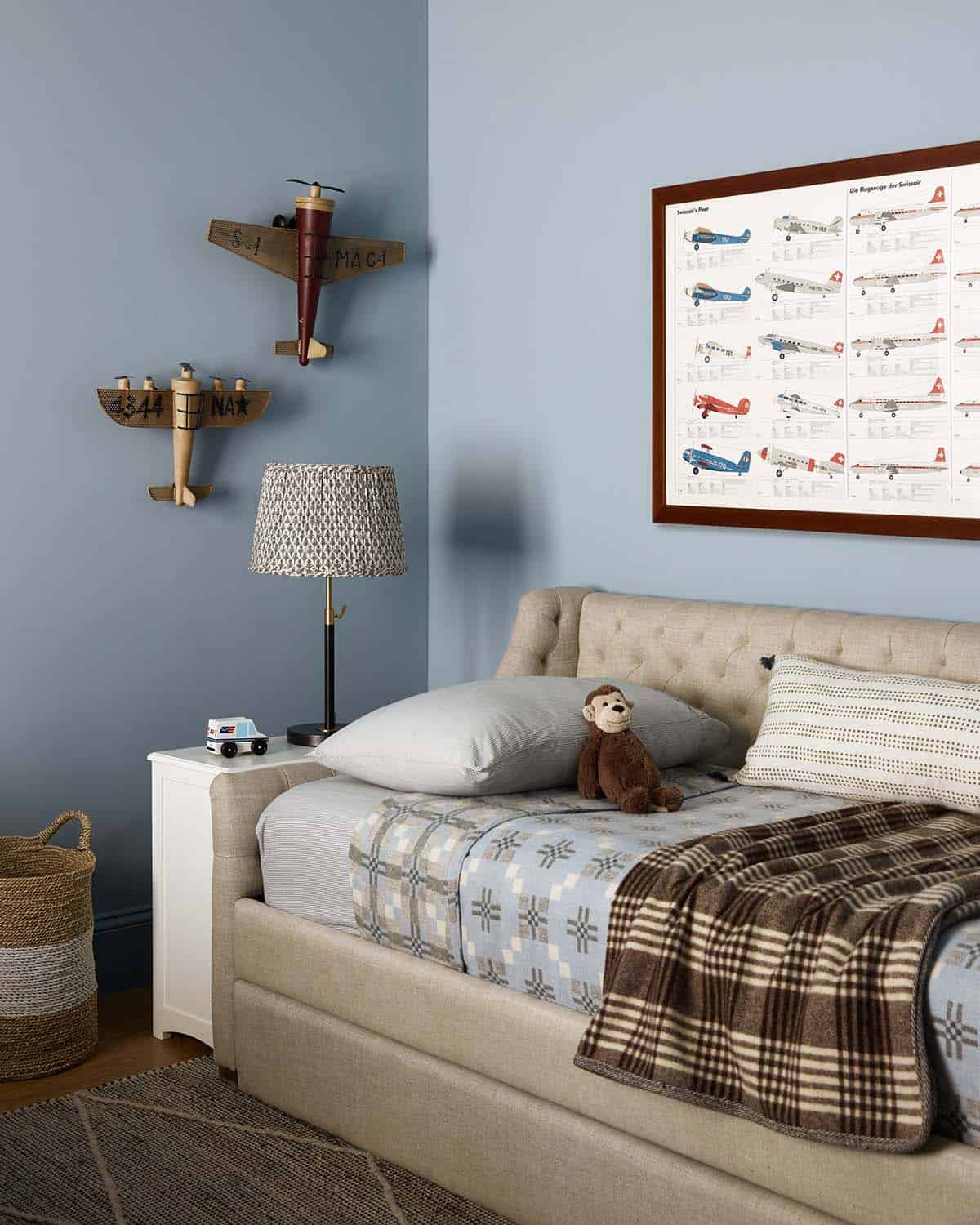 Kids room daybed with airplane models and plaid wool throw