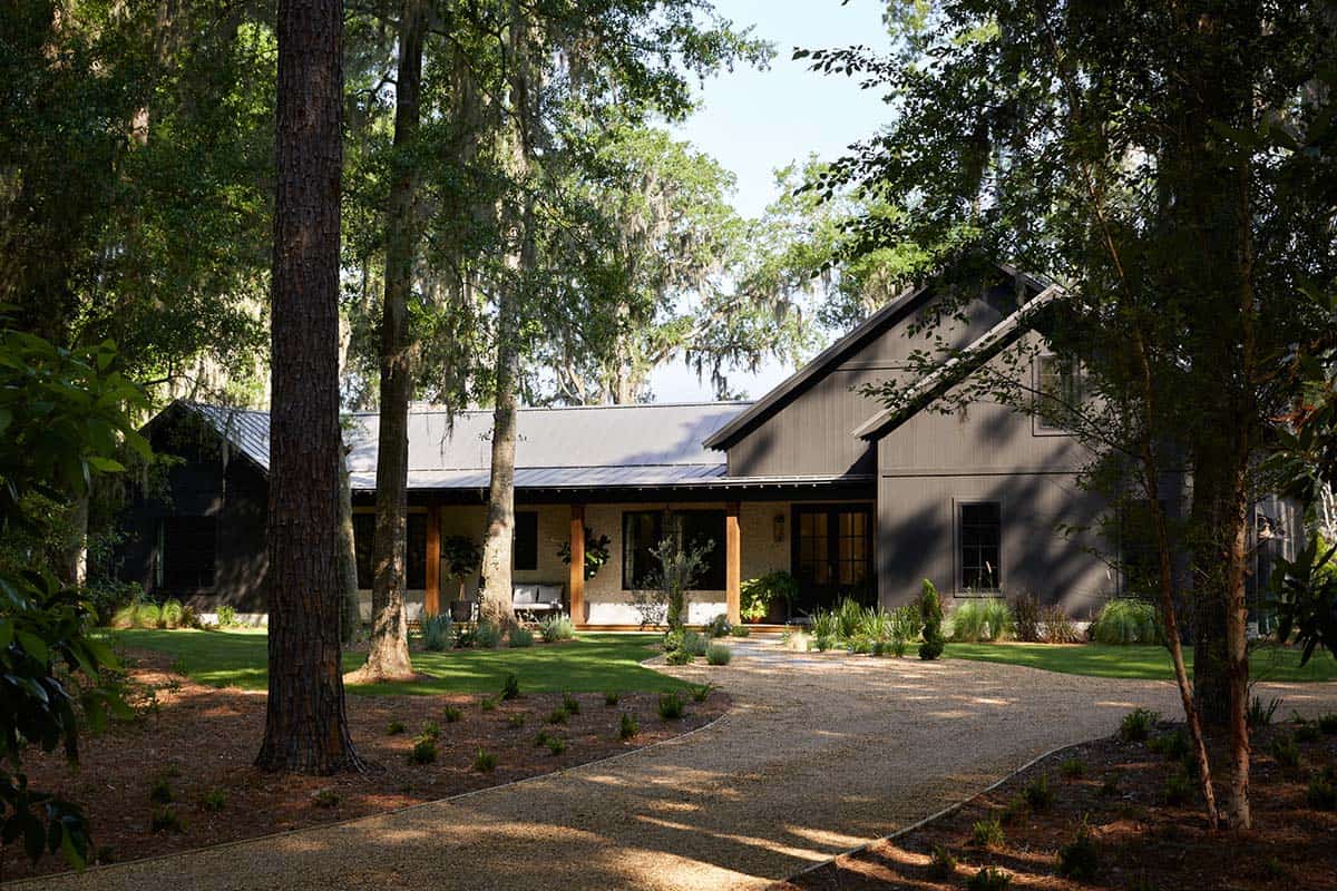 Dark board and batten farmhouse exterior framed by live oaks