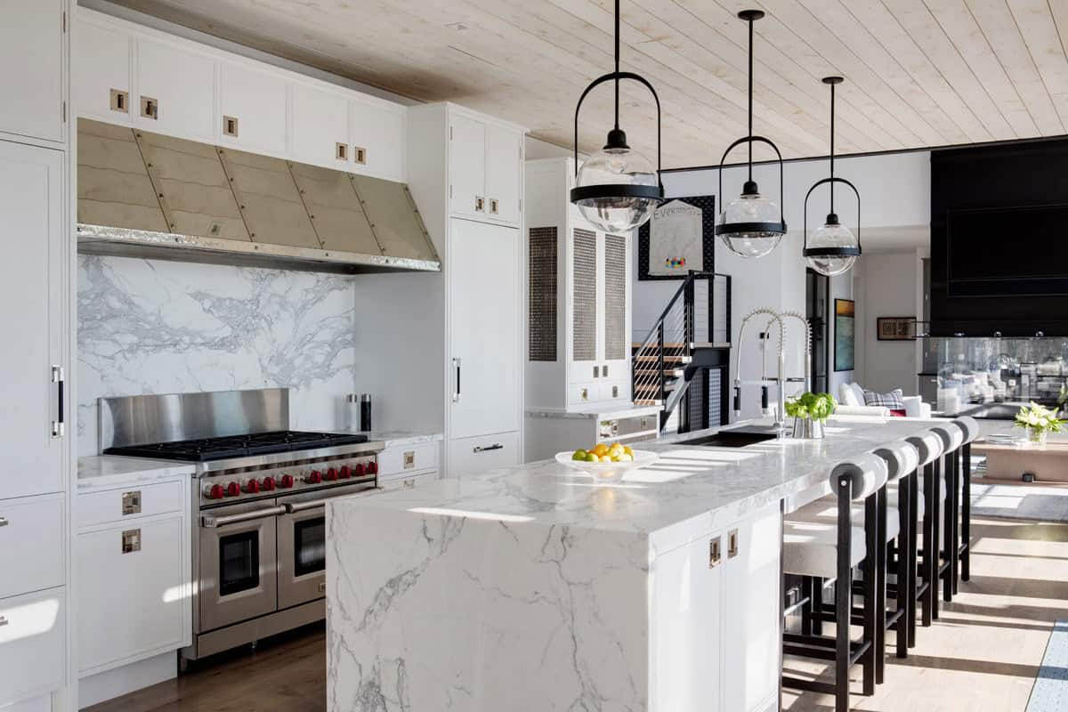 Kitchen with marble backsplash, waterfall island, and pendant lighting