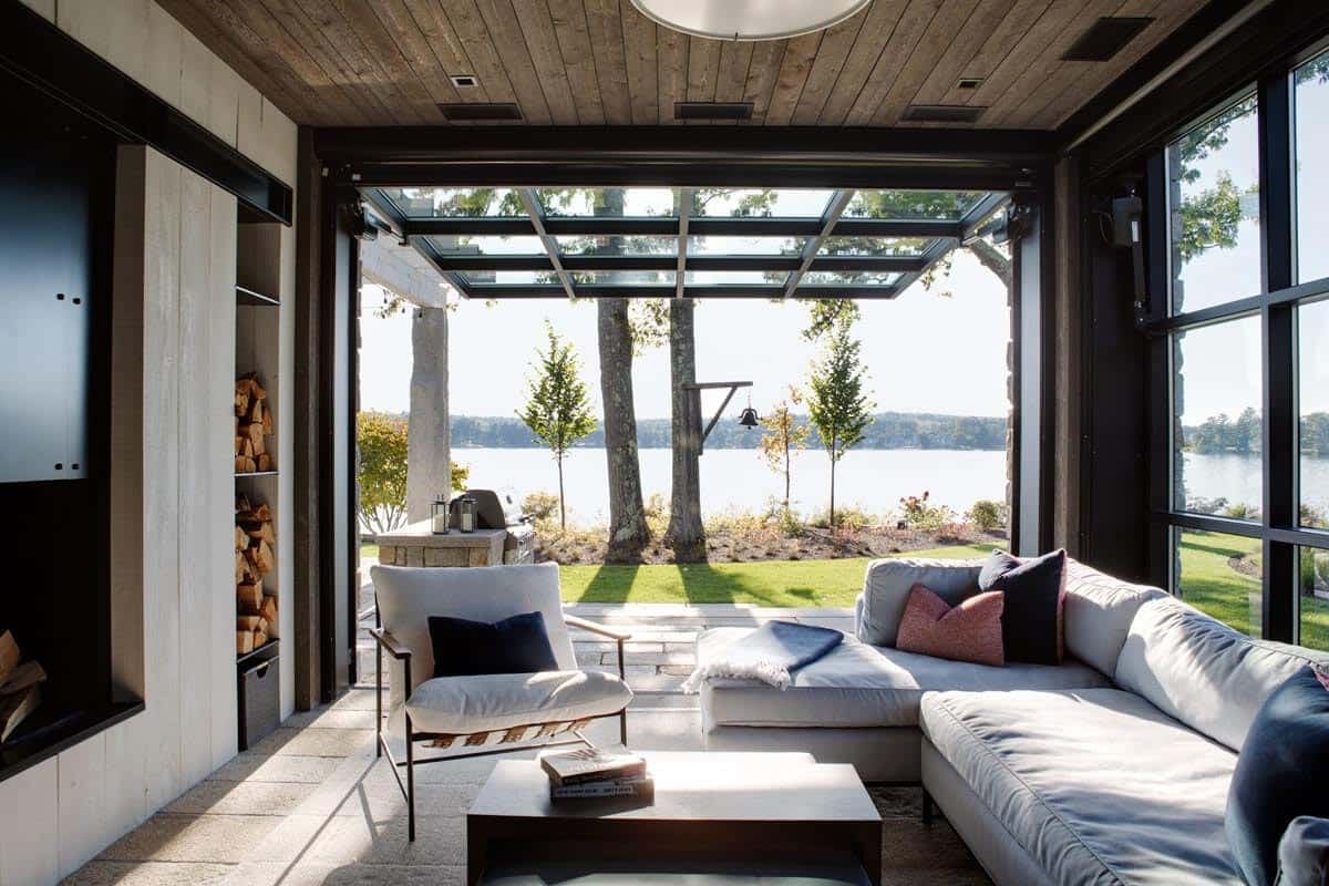 Glass-enclosed sunroom opening to lakefront patio and firewood storage
