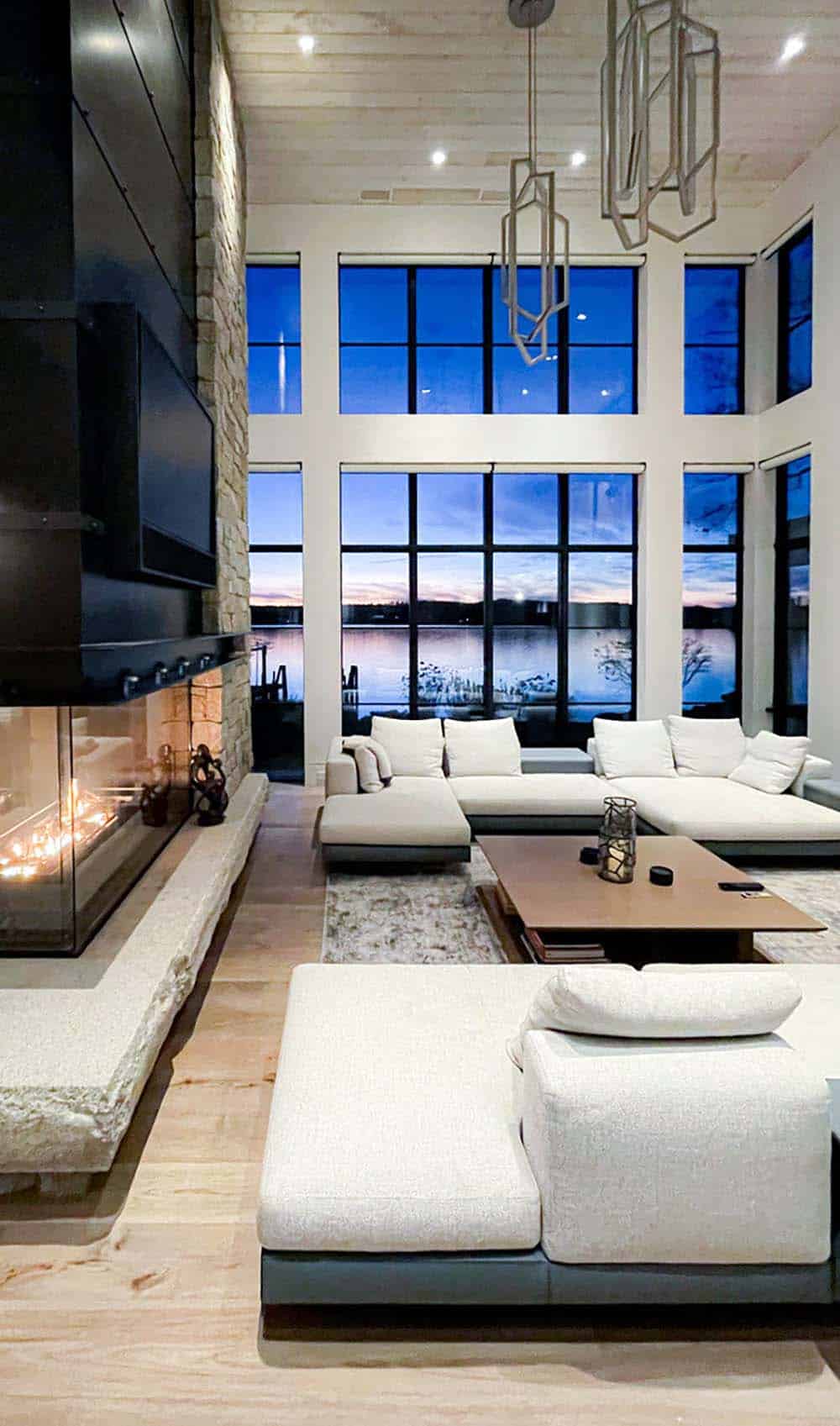 Living room with linear fireplace and dusk lake view