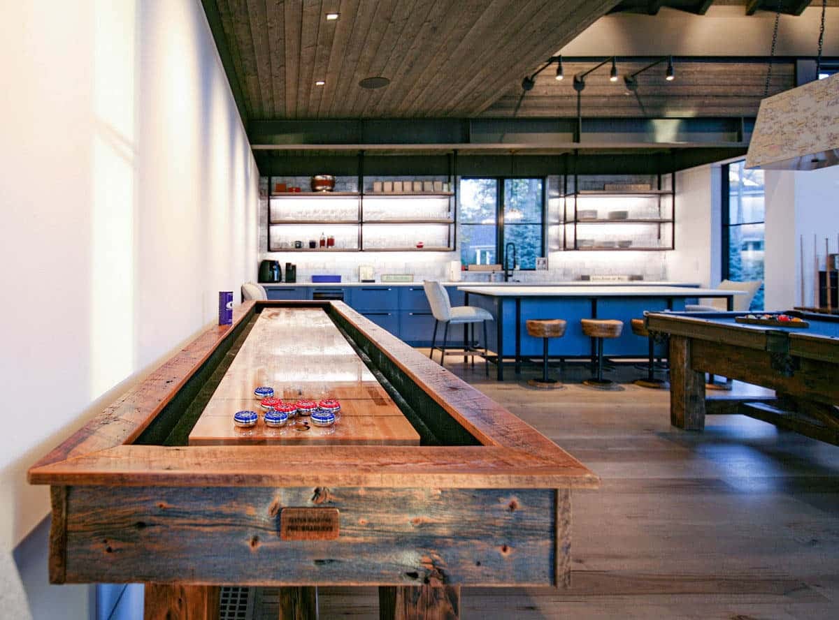 Game room with reclaimed wood shuffleboard table and blue kitchenette