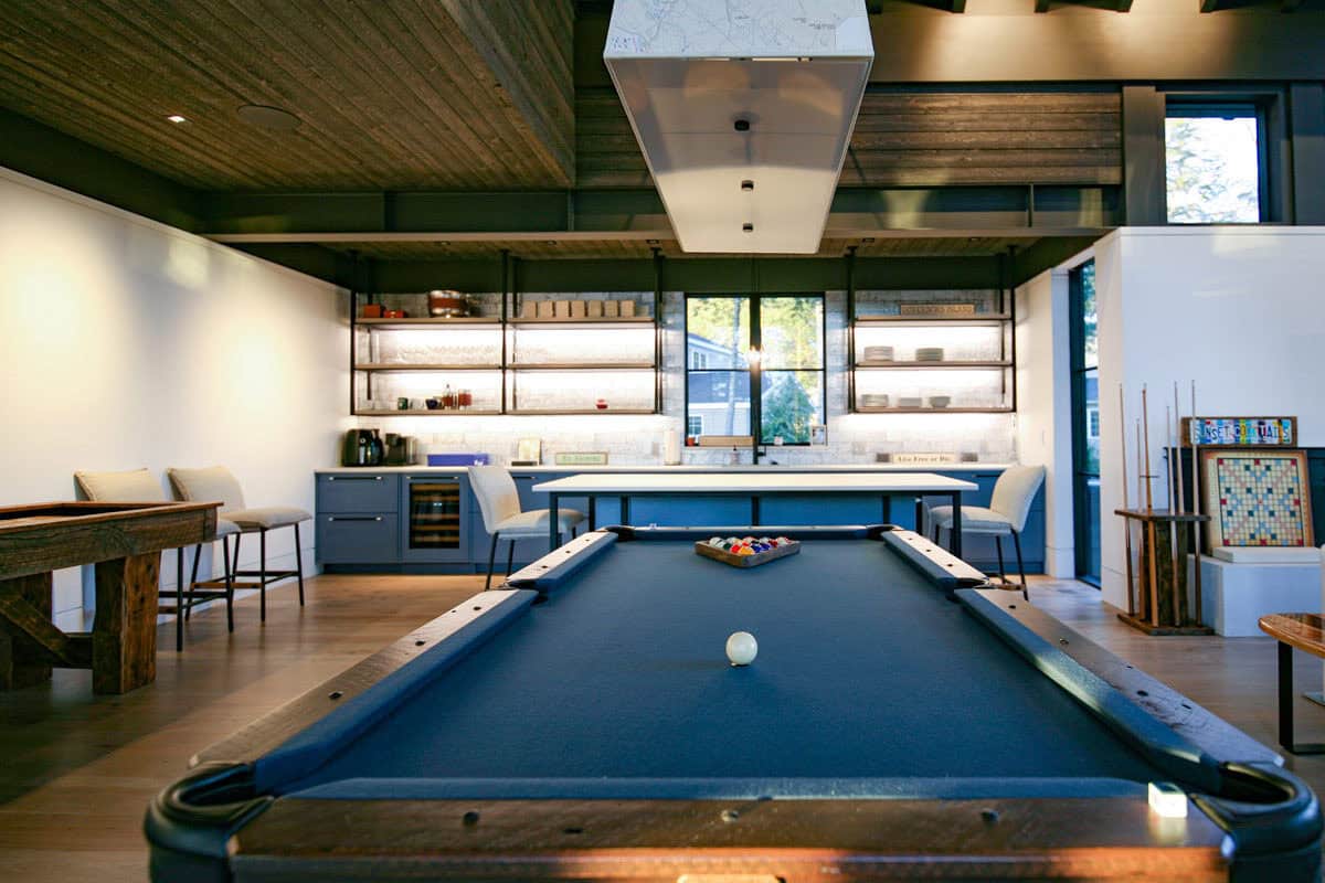 Pool table with racked balls beneath map-print pendant light