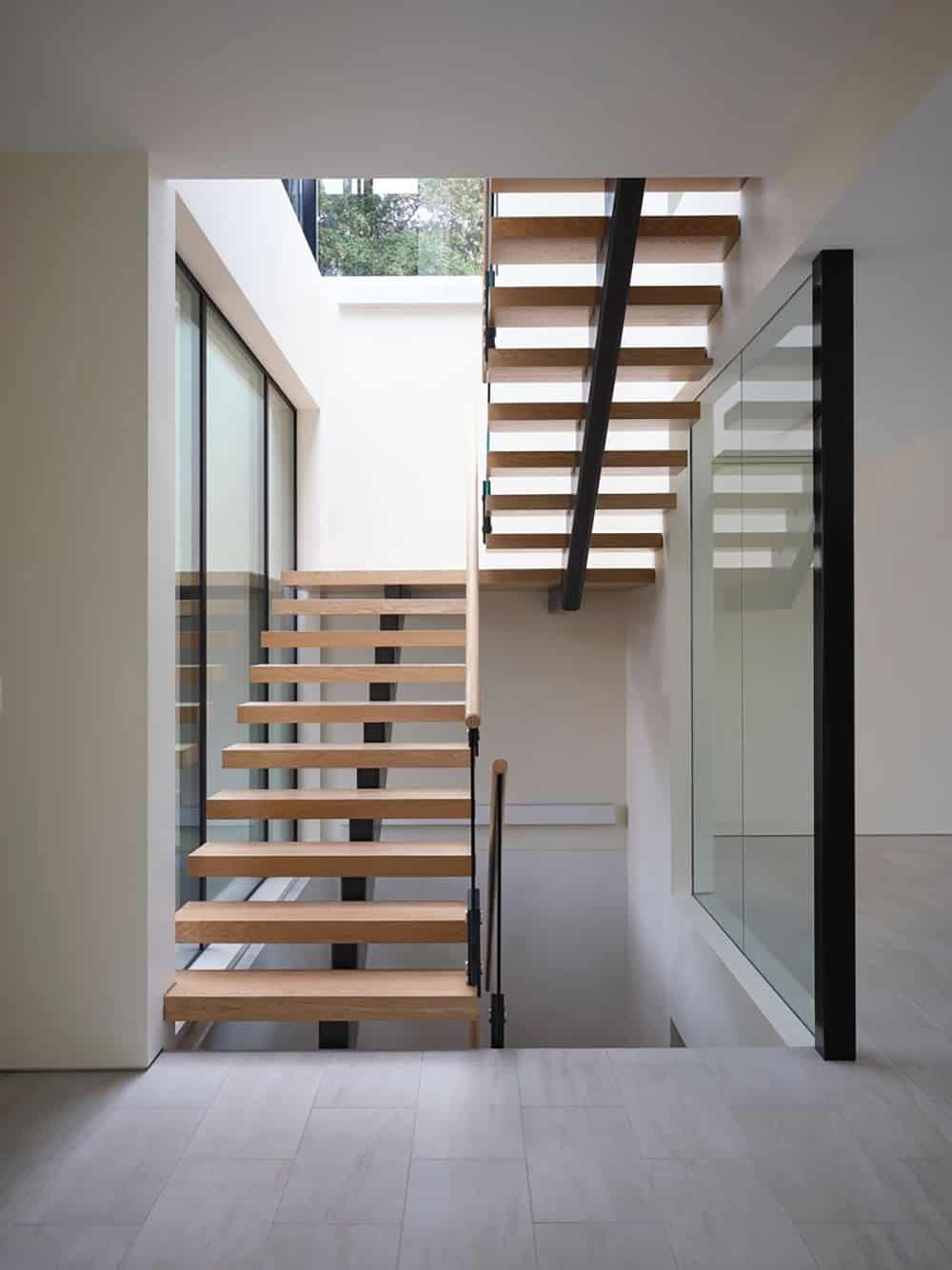 Interior view of the floating wood stairwell lit by the glass lantern above