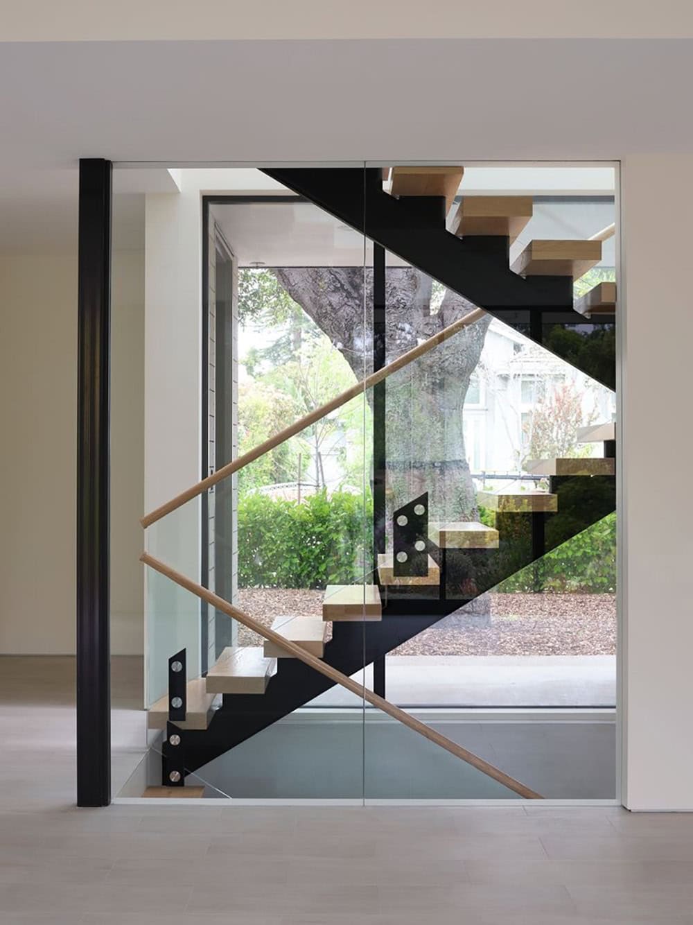 Glass-walled stairwell framing a view of the preserved oak tree outside