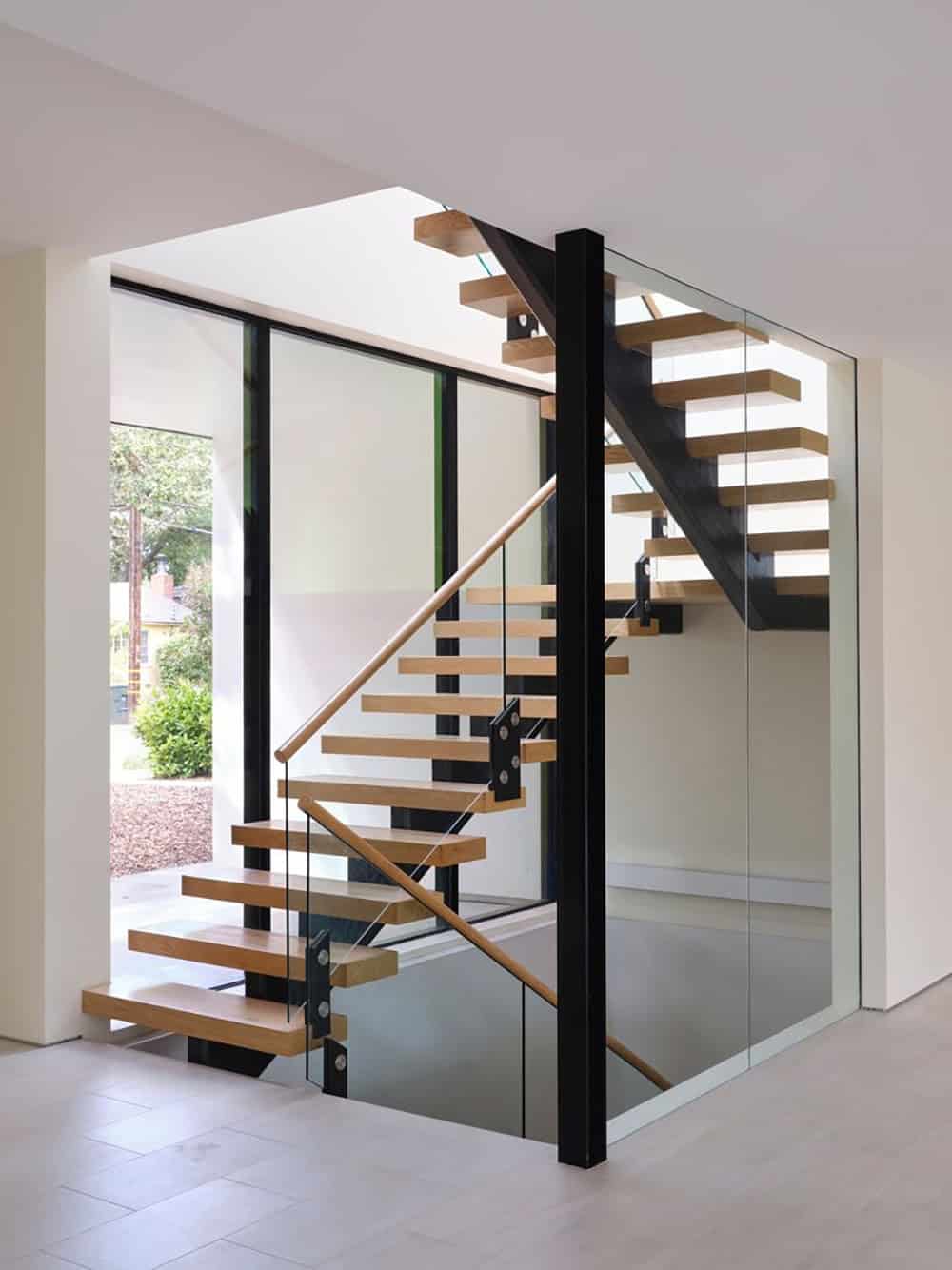 Wood and steel staircase inside the glass lantern, daylight pouring in