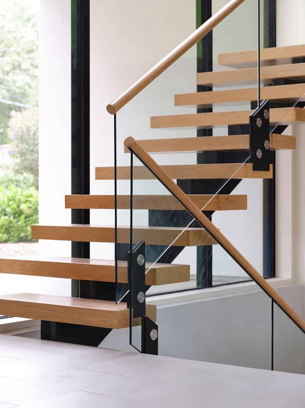 Detail of oak stair treads with glass railing and steel hardware