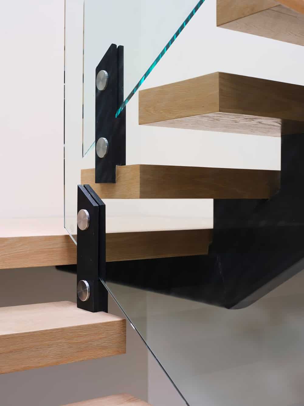 Close-up of steel stair bracket joining wood treads and glass panel