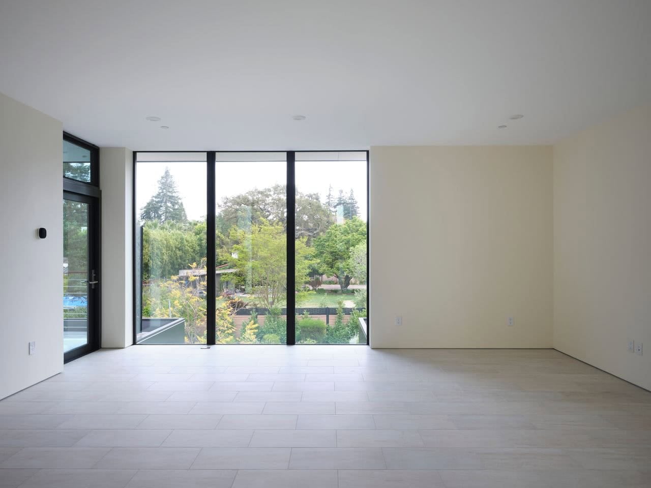 Empty bedroom with floor-to-ceiling windows overlooking the rear yard