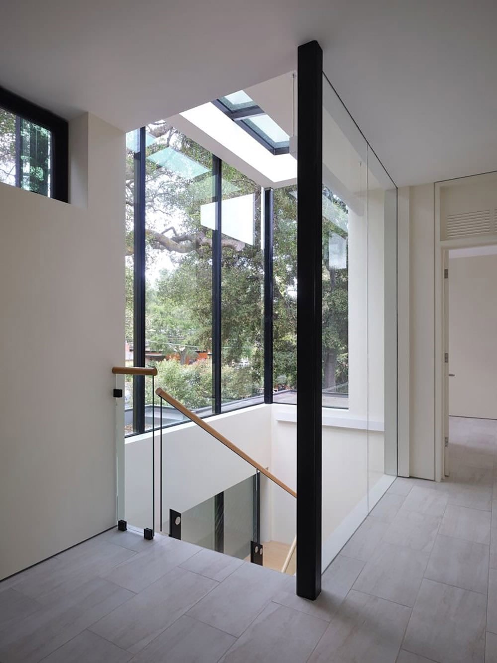 Upper-level hallway with glass-enclosed stairwell and skylight above