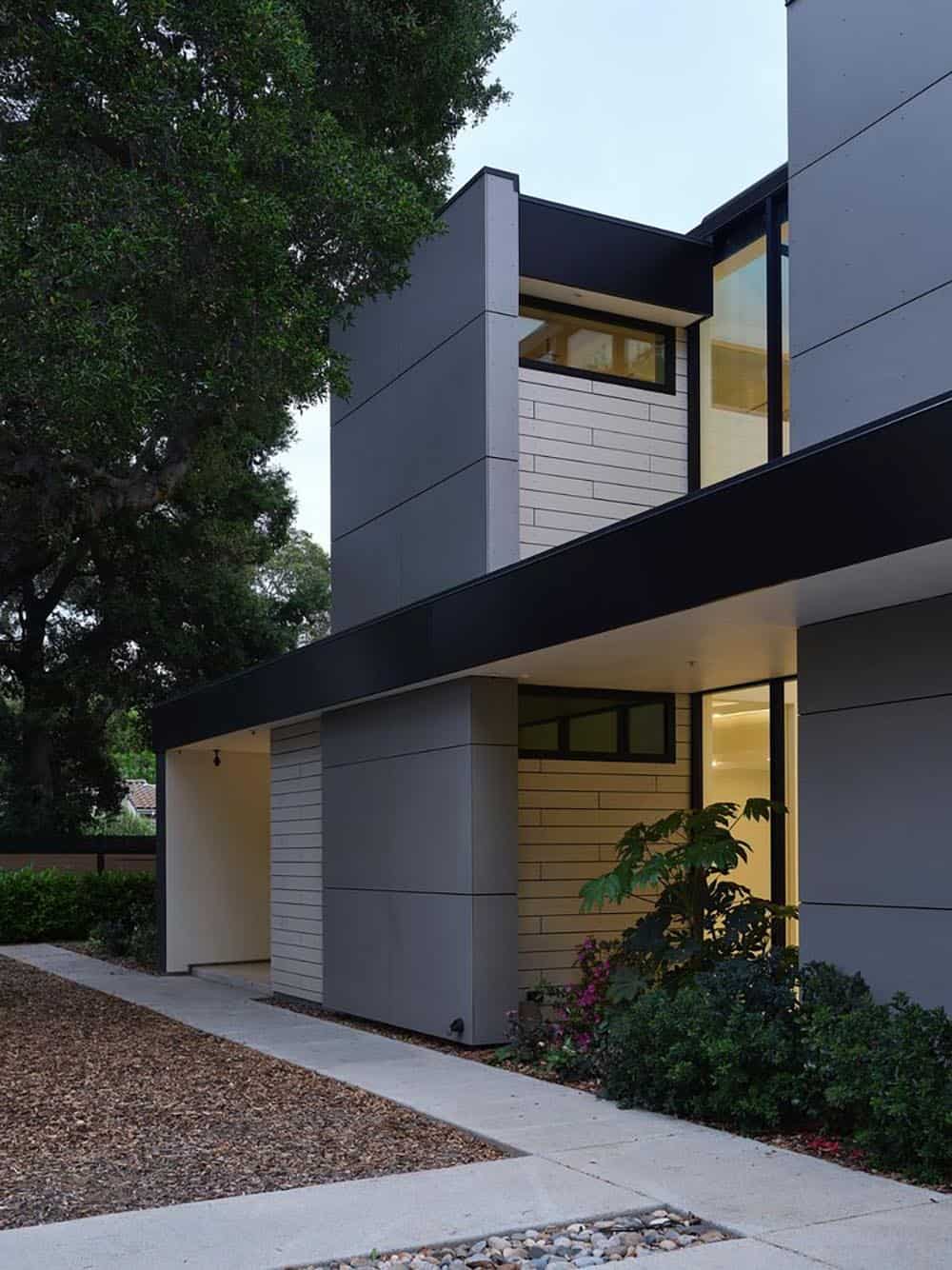 Twilight exterior corner showing carport, siding, and glowing windows