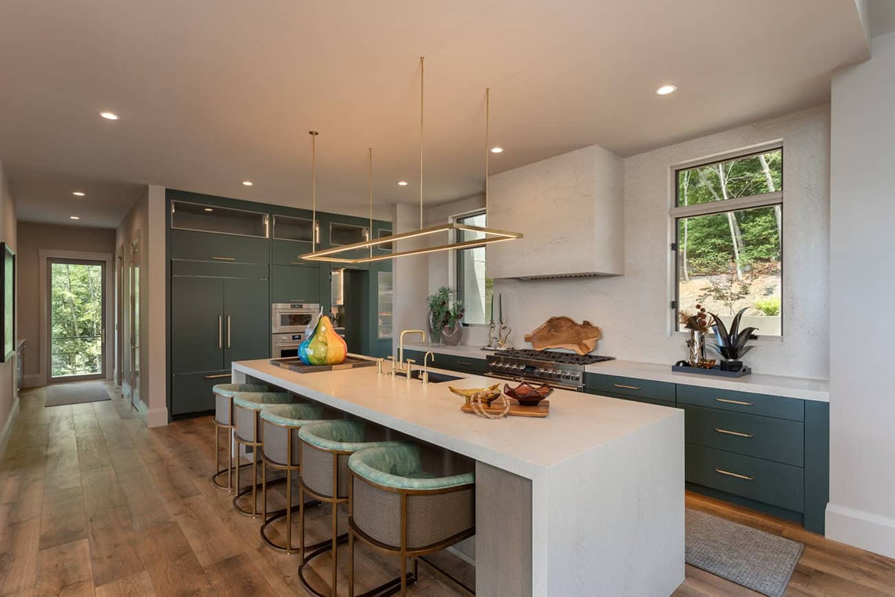 Green island kitchen with brass pendant frame and teal woven counter stools