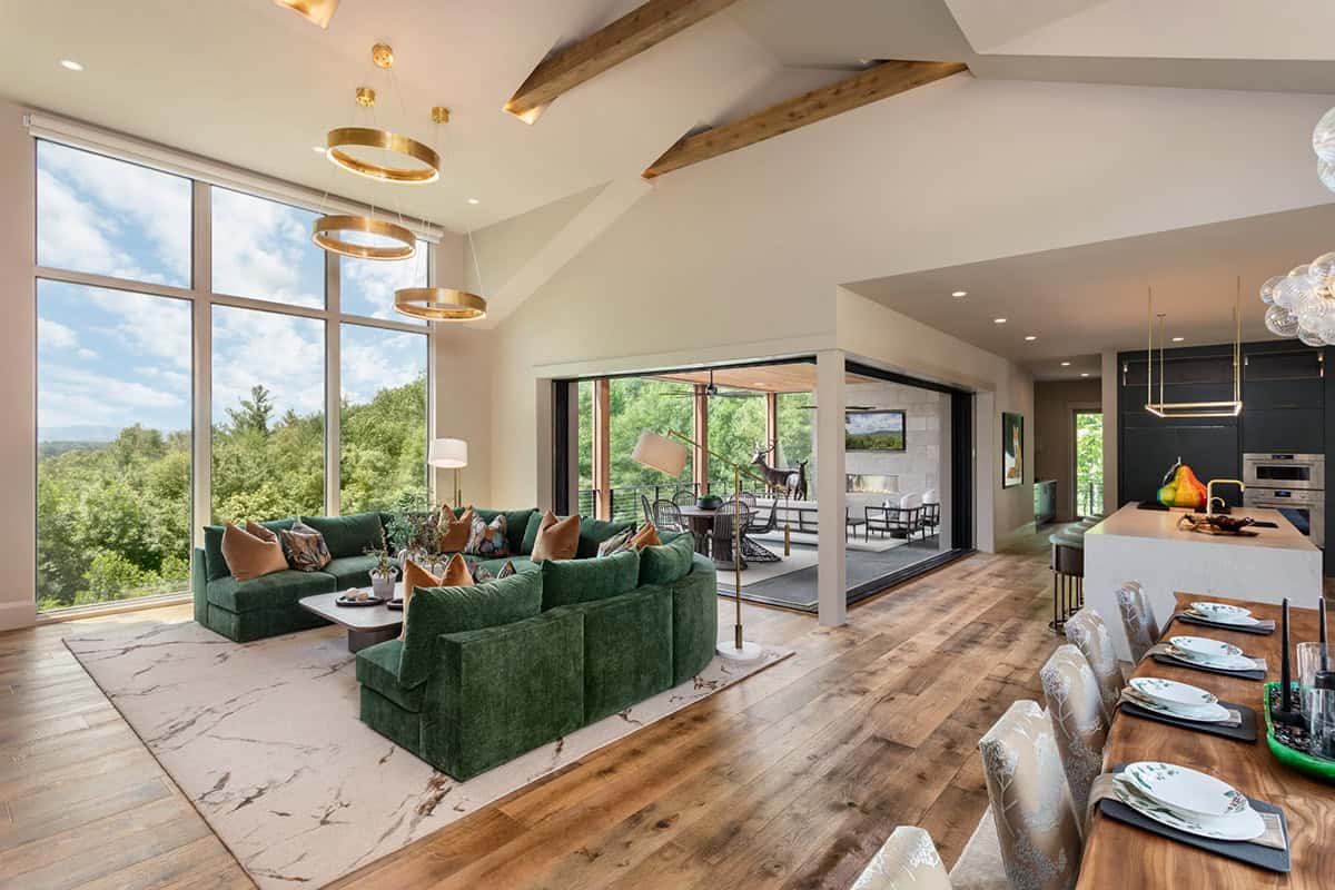 Open concept living and kitchen area framed by tall glass walls and beams