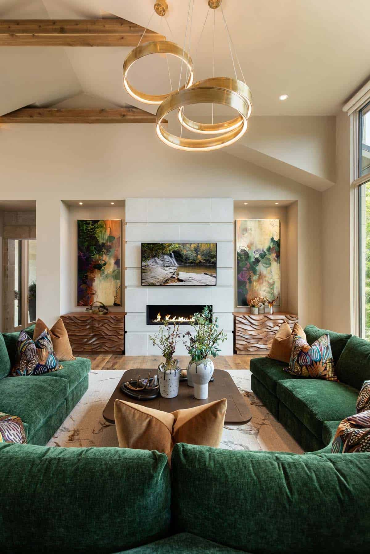 Green sectional sofa facing linear fireplace beneath modern brass ring chandelier