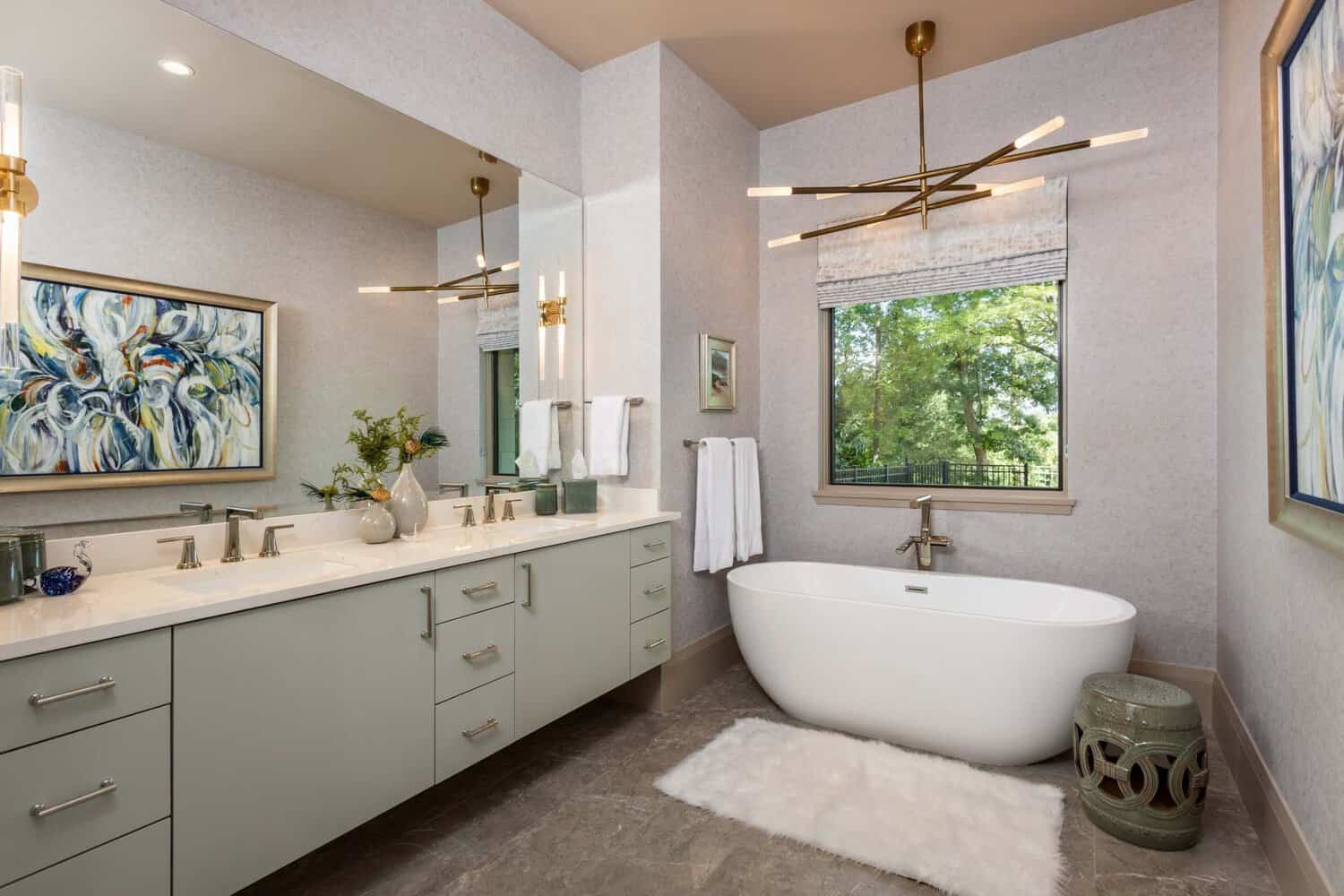 Primary bathroom with sage vanity, freestanding tub, and wooded window view