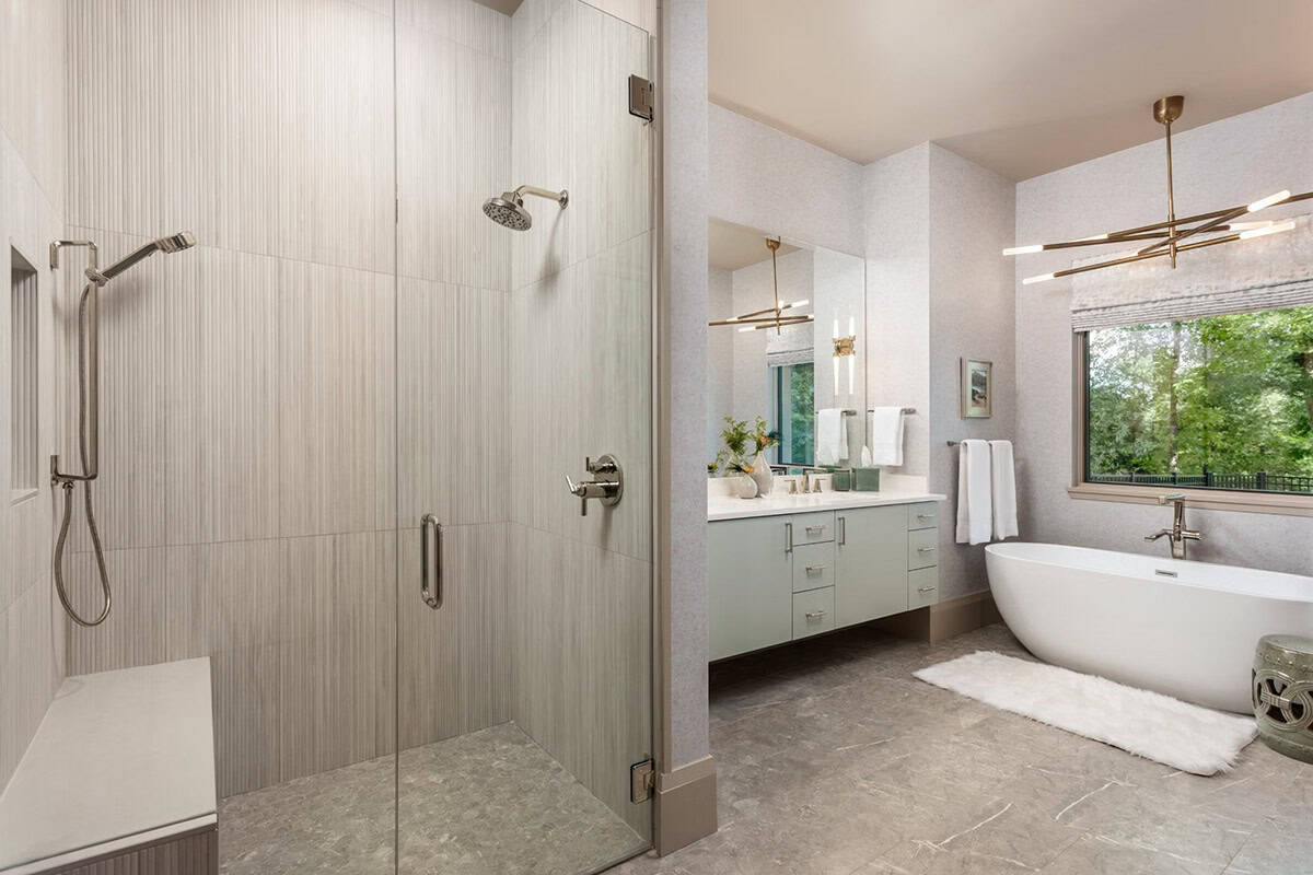 Primary bathroom shower and vanity area with freestanding soaking tub