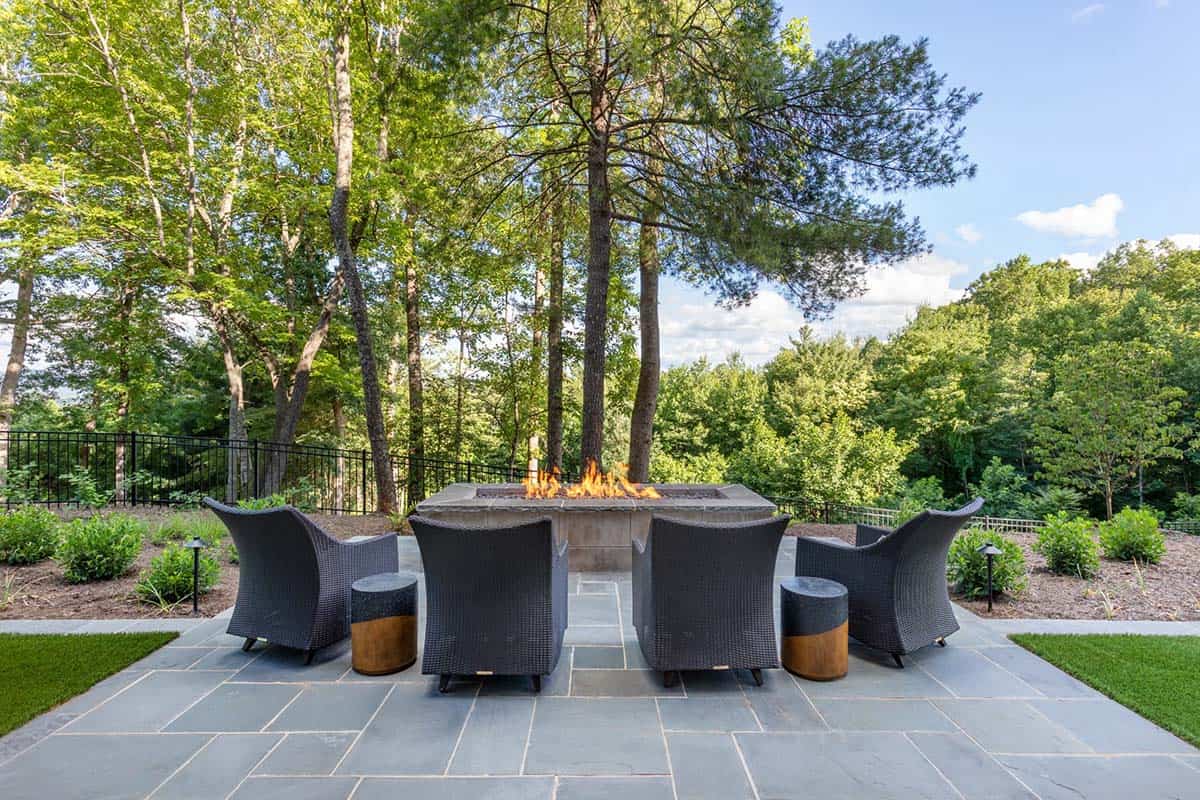 Stone patio fire pit seating area surrounded by mature pine trees